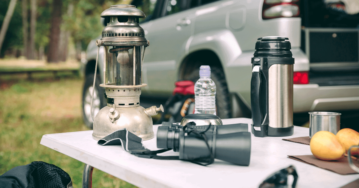a camping table with binoculars, a lantern and other items on it