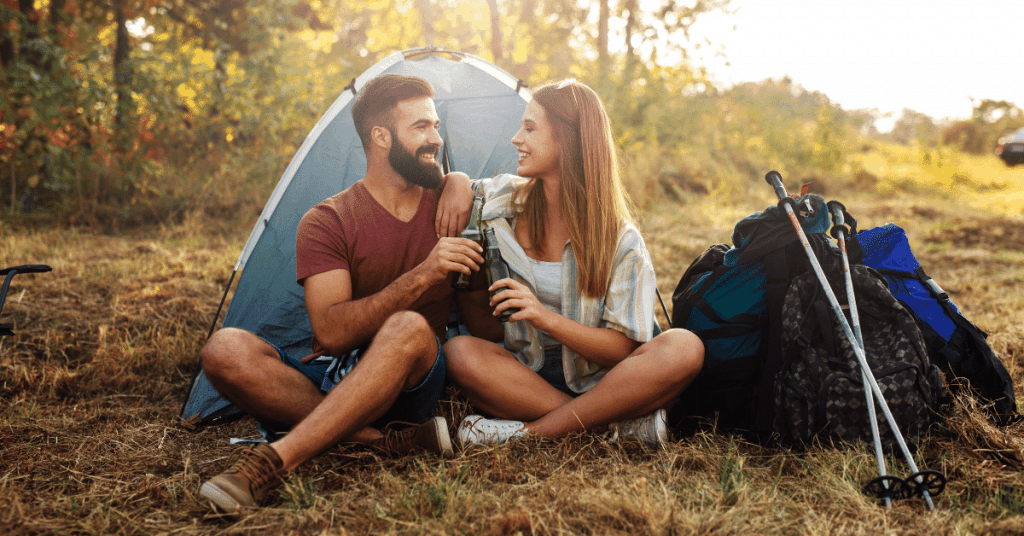 couple sitting in front of a tent having a beer