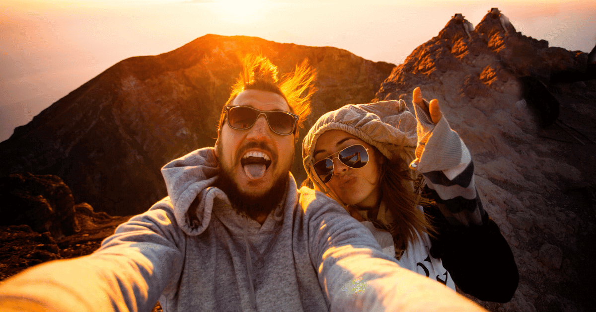 casal tirando selfie no topo de uma montanha