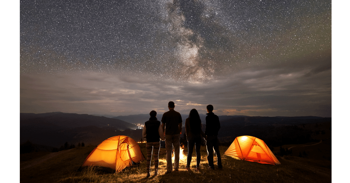 family stargazing next to tents