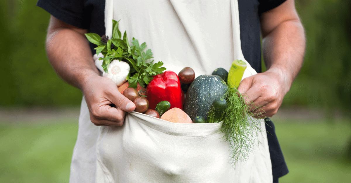 man holding apron full of vegetables