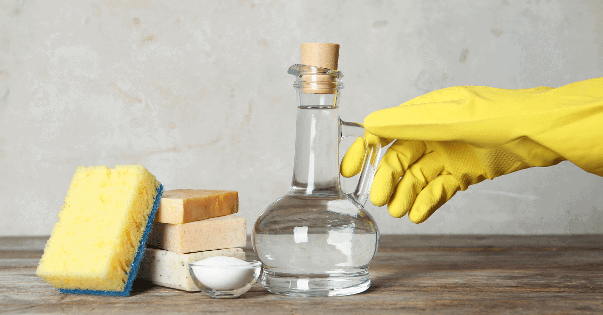 rubber glove holding vinegar next to soap and spongerubber glove holding vinegar next to soap and sponge