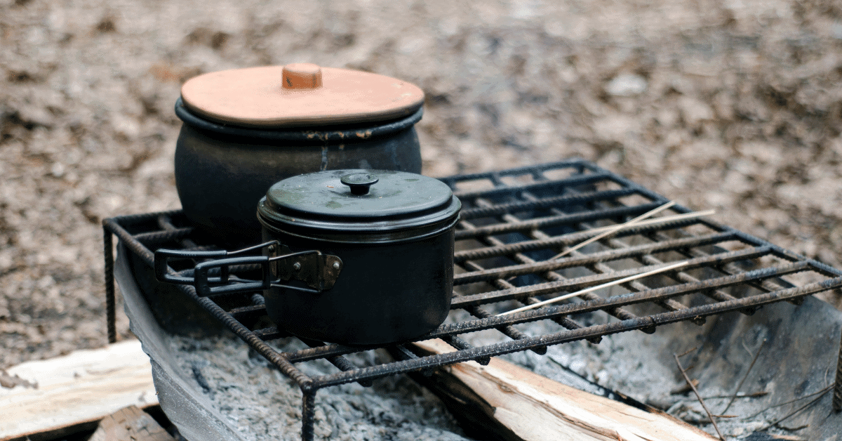 pots on a rack over a campfire