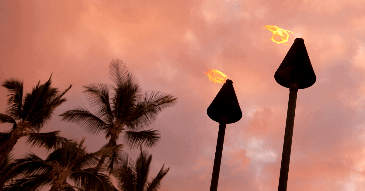 2 tiki torches with palm trees in the background