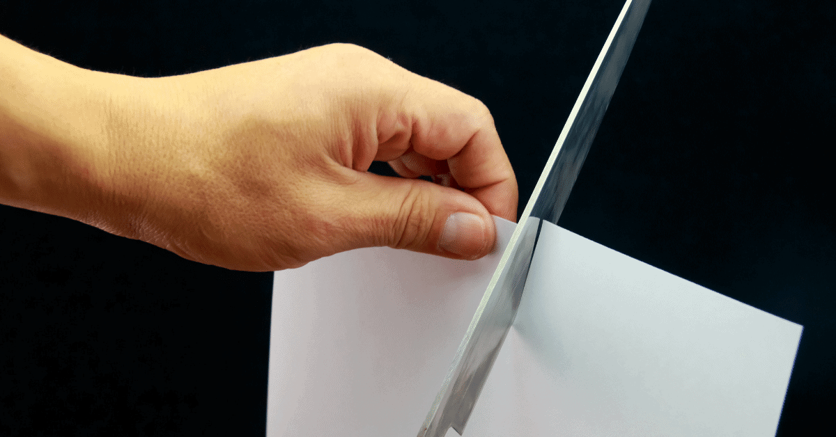 a person cutting paper with a knife to test sharpness
