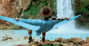 a man sitting in a hammock in front of a waterfall