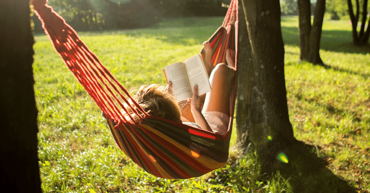 a girl lying in a hammock reading a book