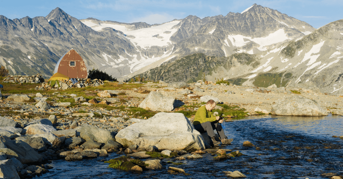 a man filtering water from a stream in the mountains