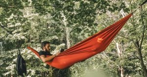 a man laying in a hammock between trees