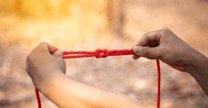 a pair of hands holding a piece of rope tied into a knot