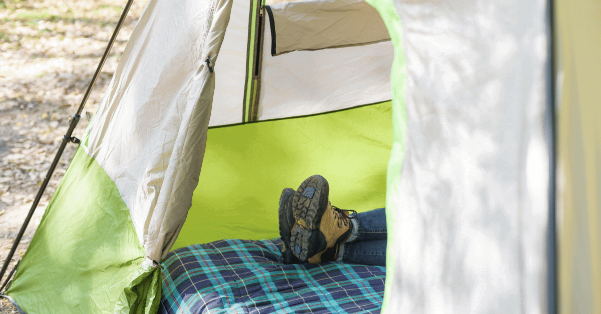 a person laying on a camping bed in a tent