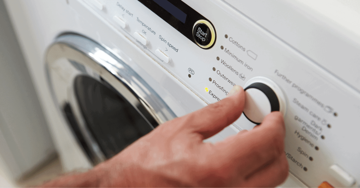 a person setting the cycle on a washing machine