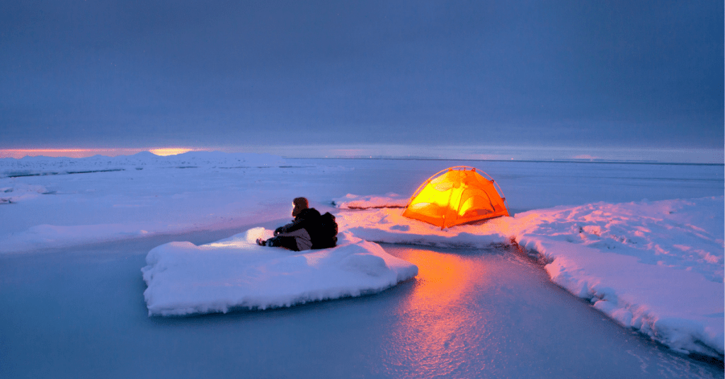 a person sitting next to a tent in an arctic setting