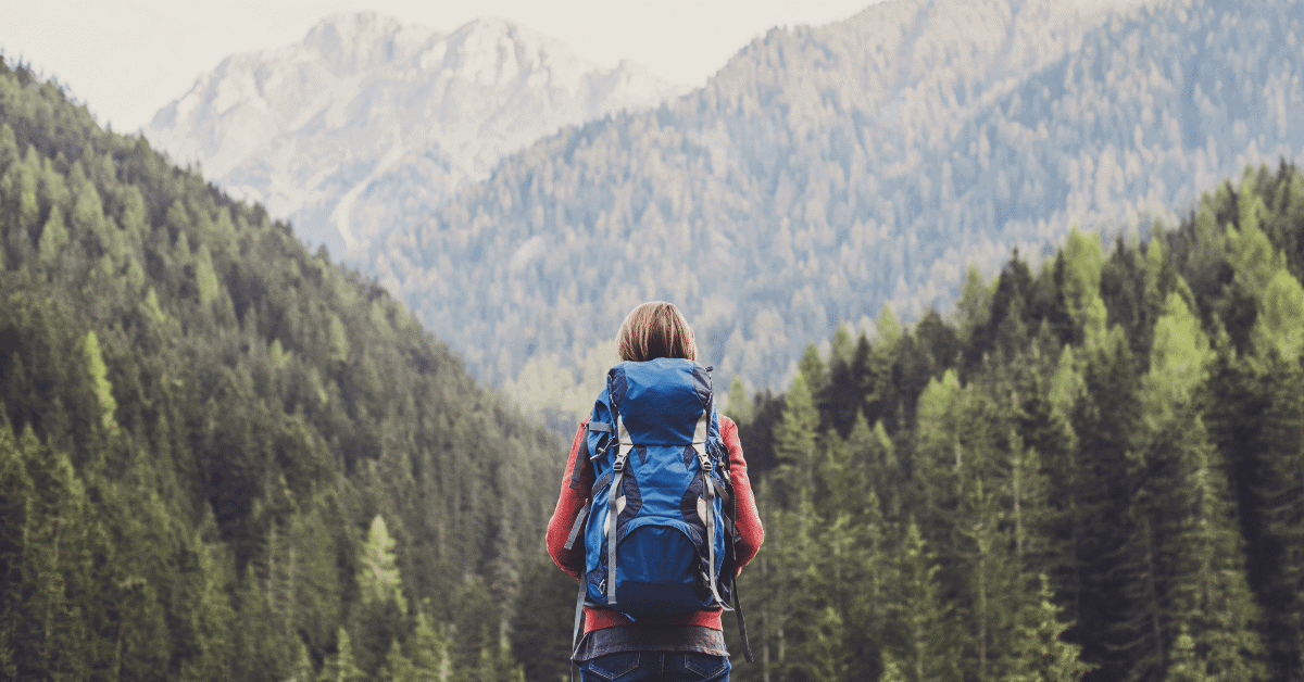 a woman wearing a hiking backpack in the mountains