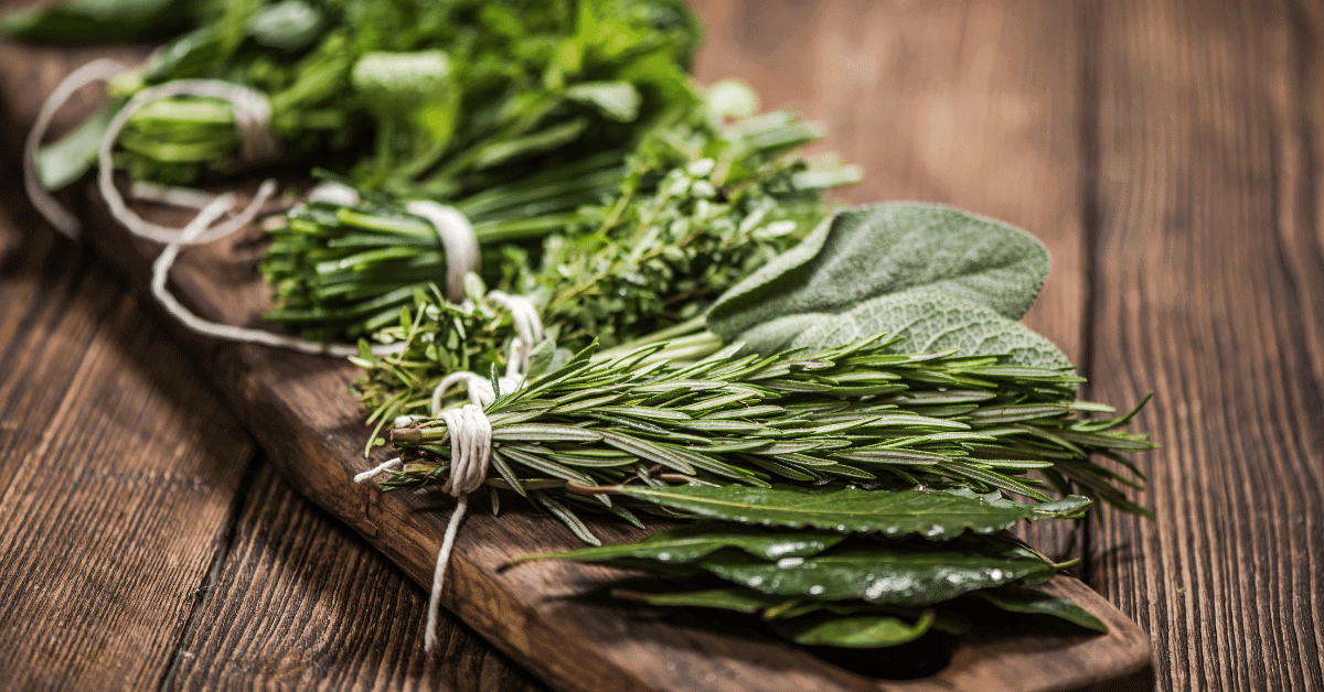 an assortment of fresh herbs on a wooden board