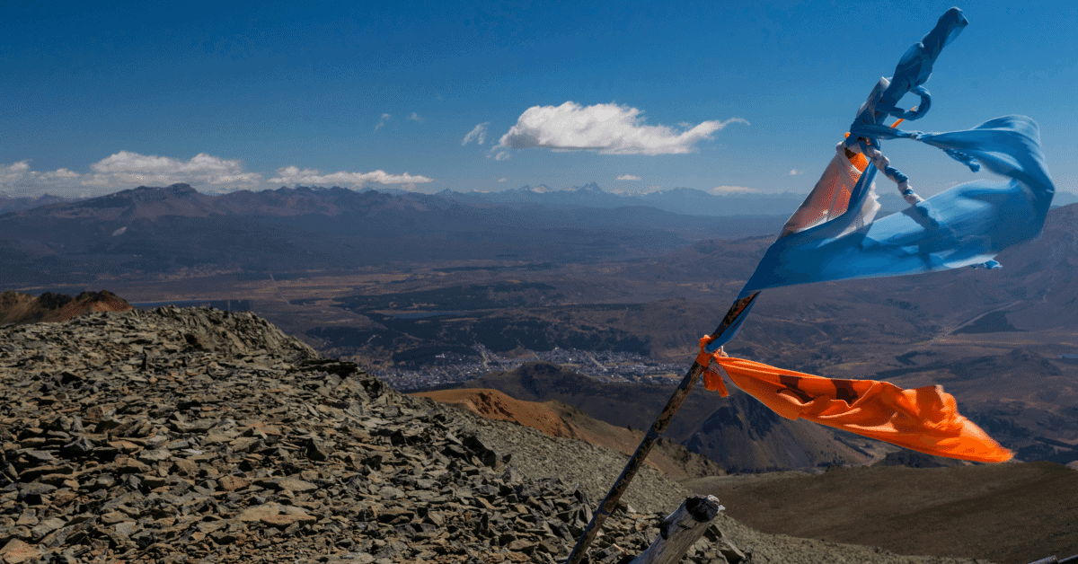 flags blowing in the wind on top of a mountain