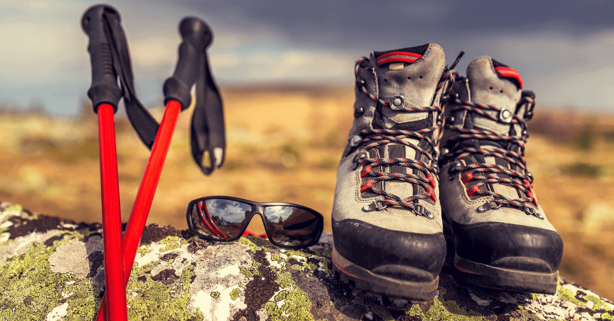 hiking boots sunglasses and trekking poles