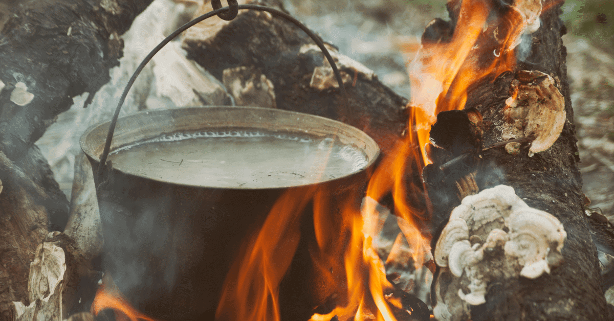 water boiling in a pot over a campfire