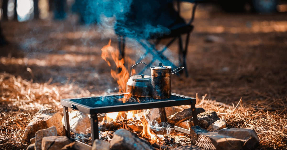 2 pots of water boiling over a campfire