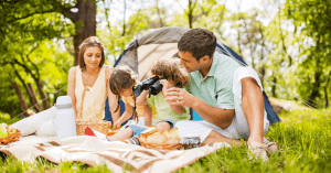 a family sitting in front of their tent at a campsite