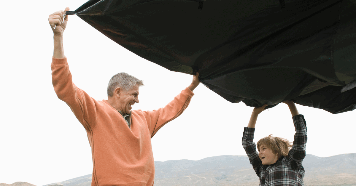 a father and son unpacking a tent footprint