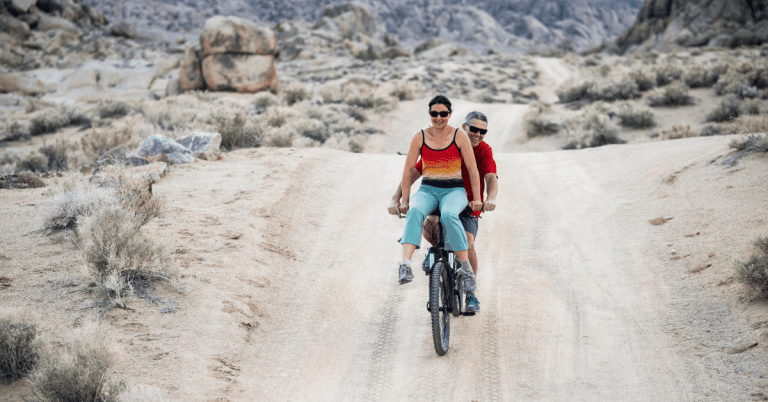 a man and a woman riding a bicycle through a desert landscape