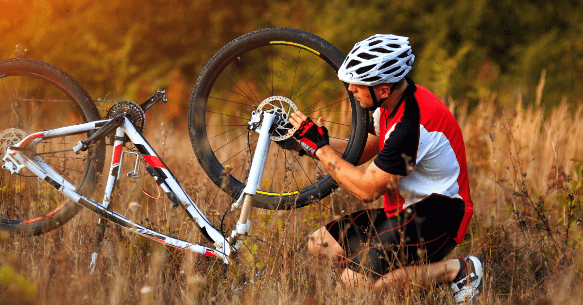 a man repairing his bicycle on a trail