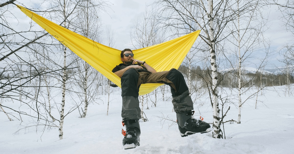 a man wearing skiing boots in a hammock in the snow