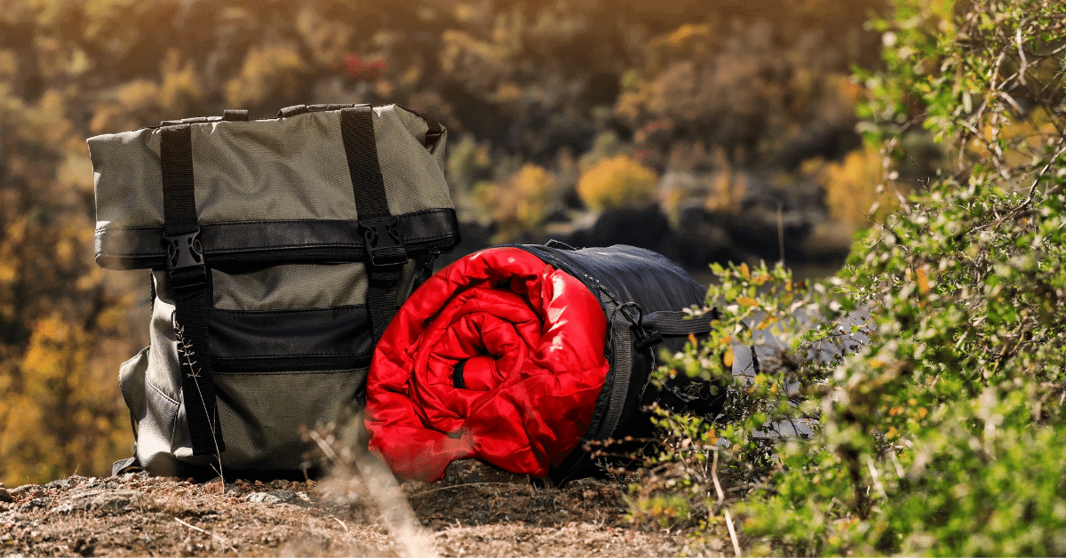 a packed sleeping bag next to a backpack