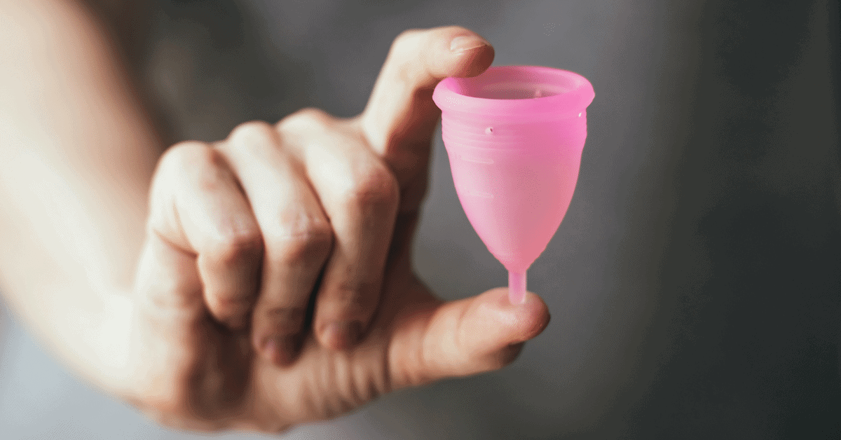 a woman holding a pink menstrual cup