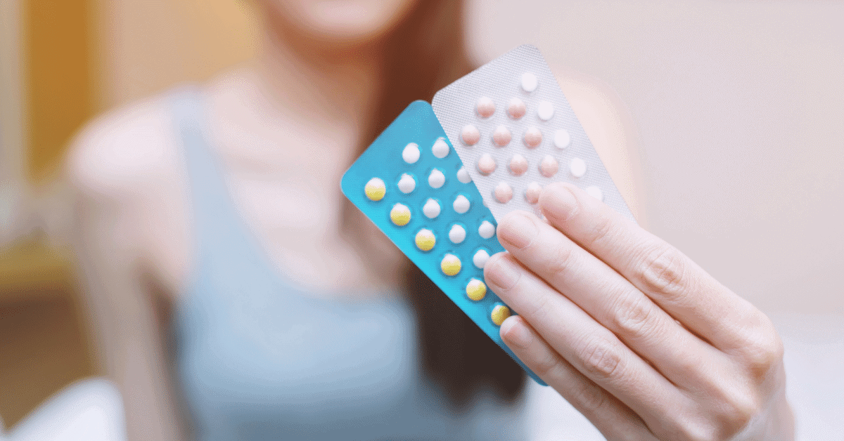 a woman holding birth control pills