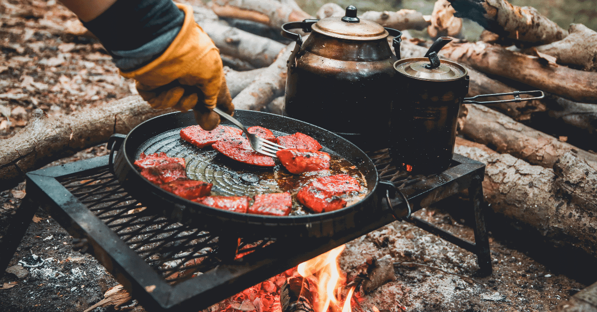 someone cooking something on a campfire grate