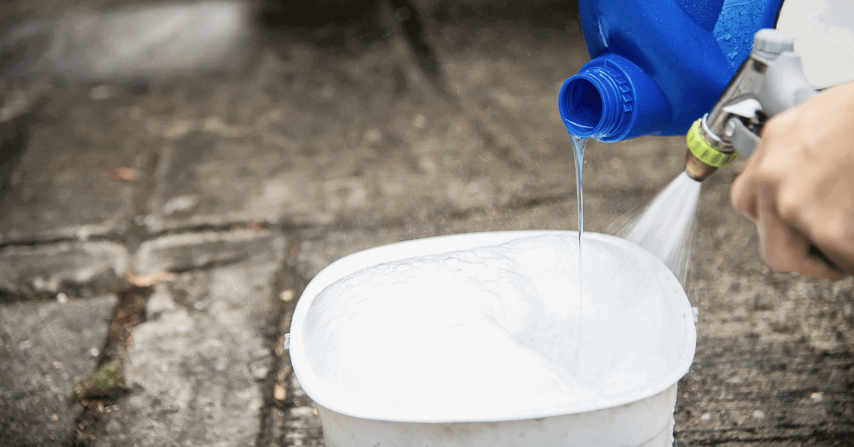 someone pouring soap and water into a bucket