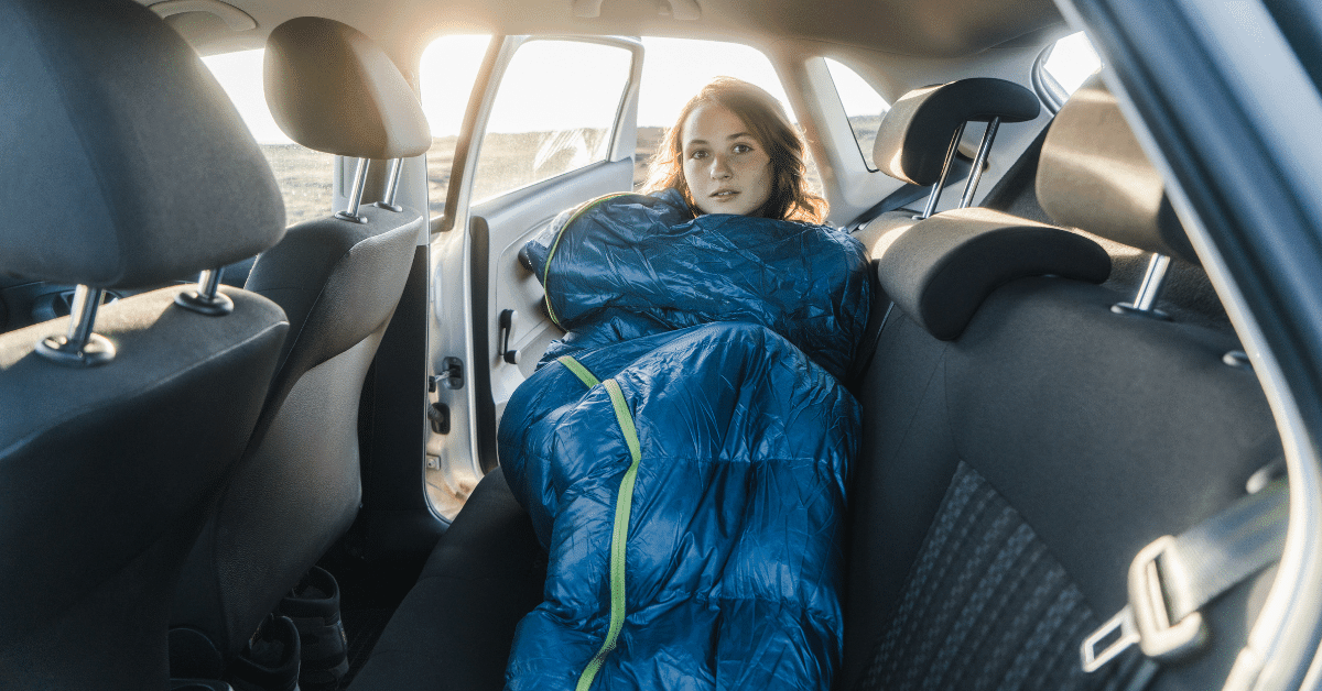 girl in the back seat of a car in a blue sleeping bag