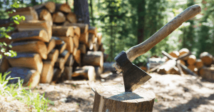 hatchet in a log with firewood in the background