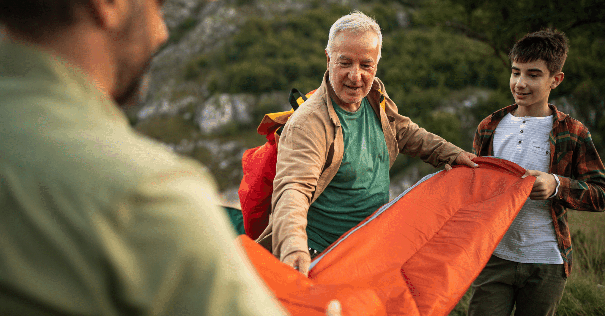 two men and a boy folding a sleeping bag