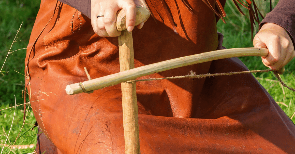 woman using a bow drill to start a fire