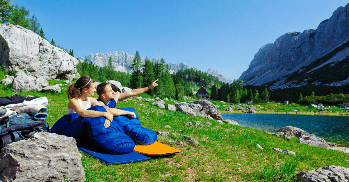 young couple in blue sleeping bags by a lake