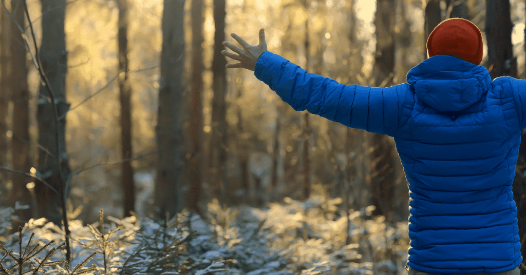 person wearing blue down jacket in the woods