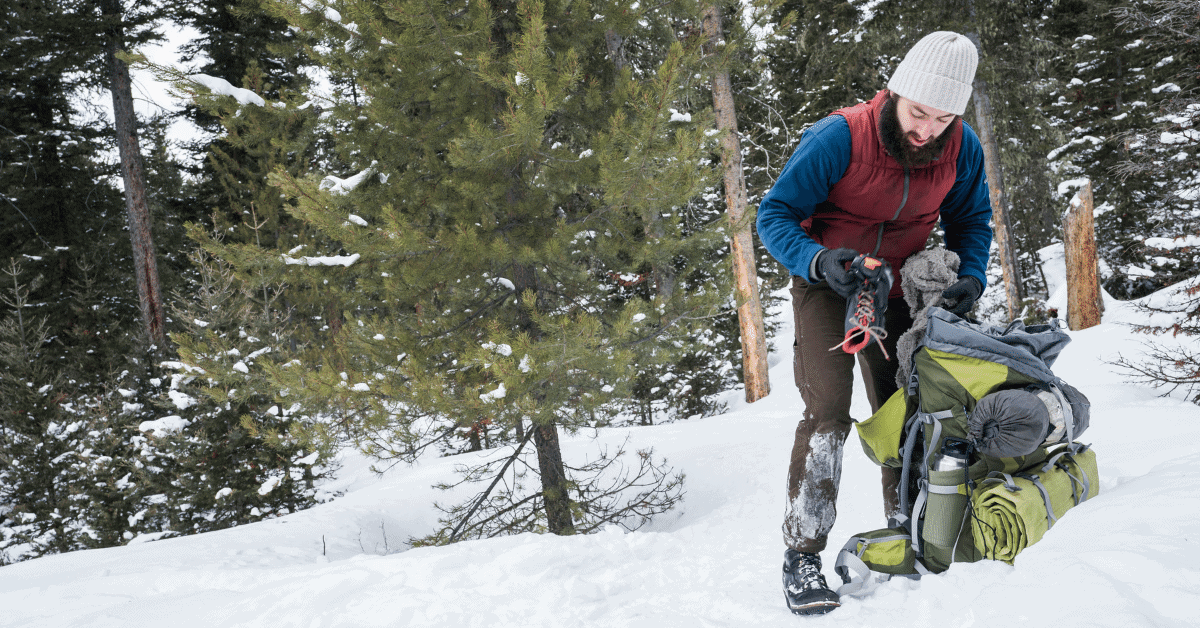 hiker packing a backpack in the snow