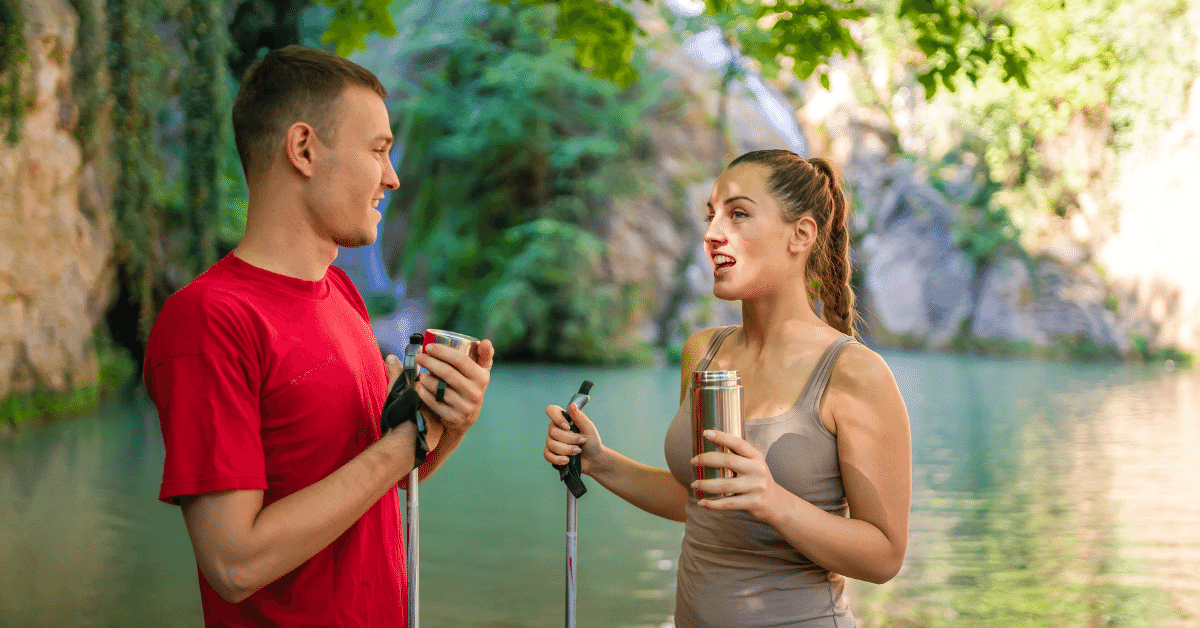 man and woman on a hike drinking water