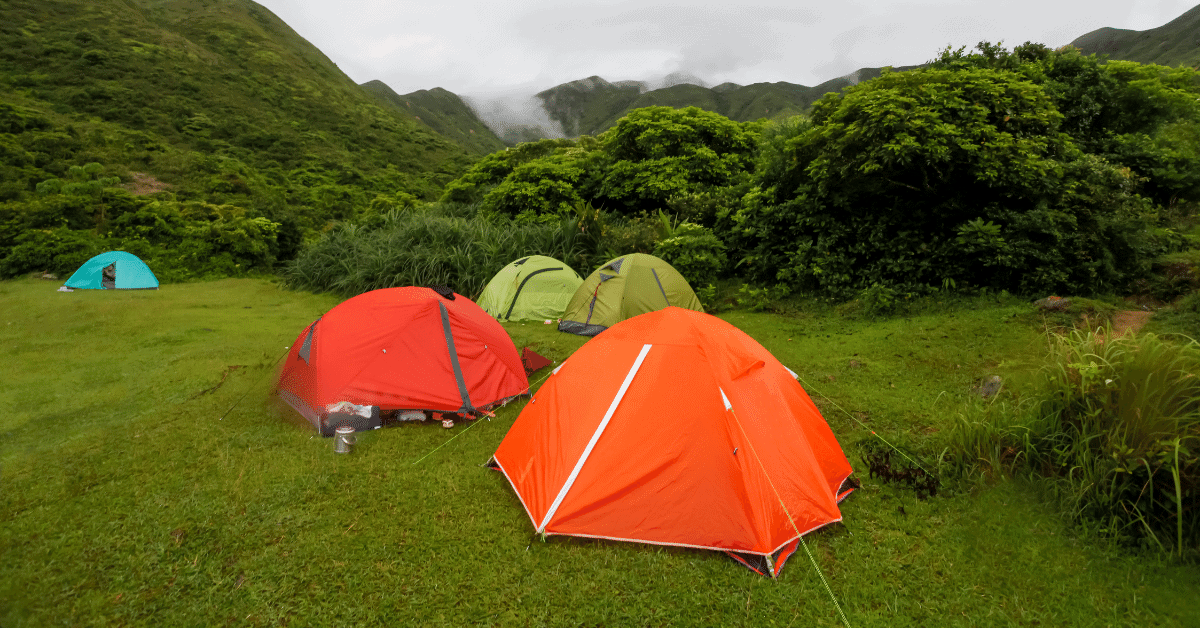 several multicolored tents in a green hilly landscape