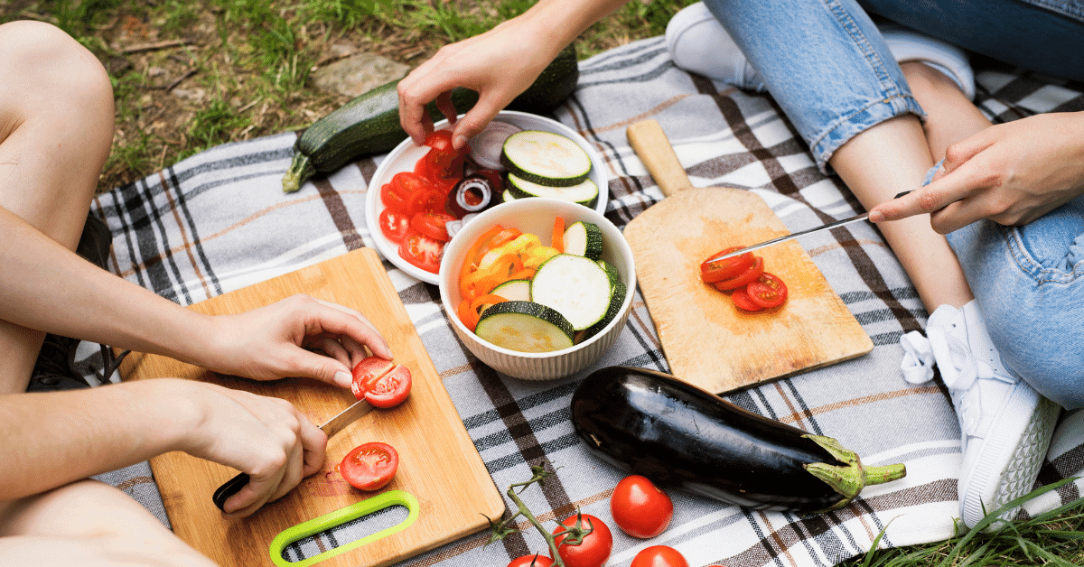 two people cutting up vegetables while camping