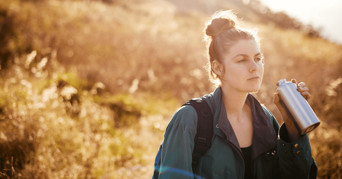 young woman drinking water on a hike