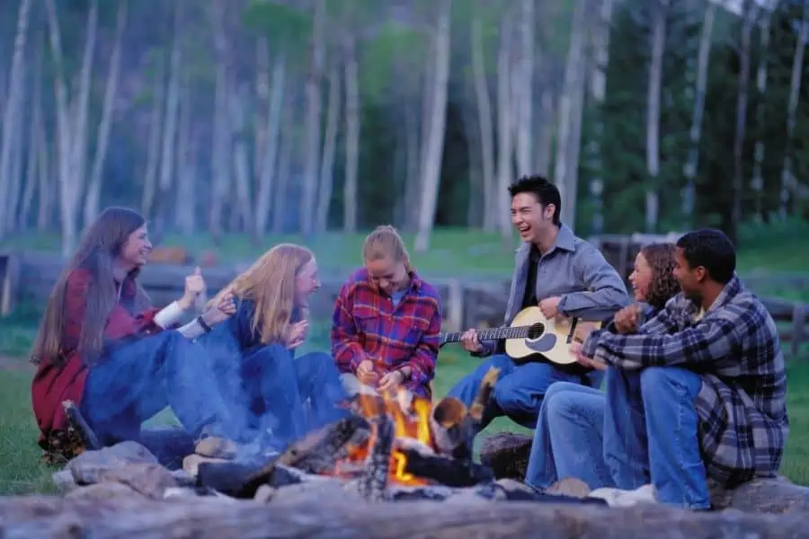 Teenagers singing with a campfire