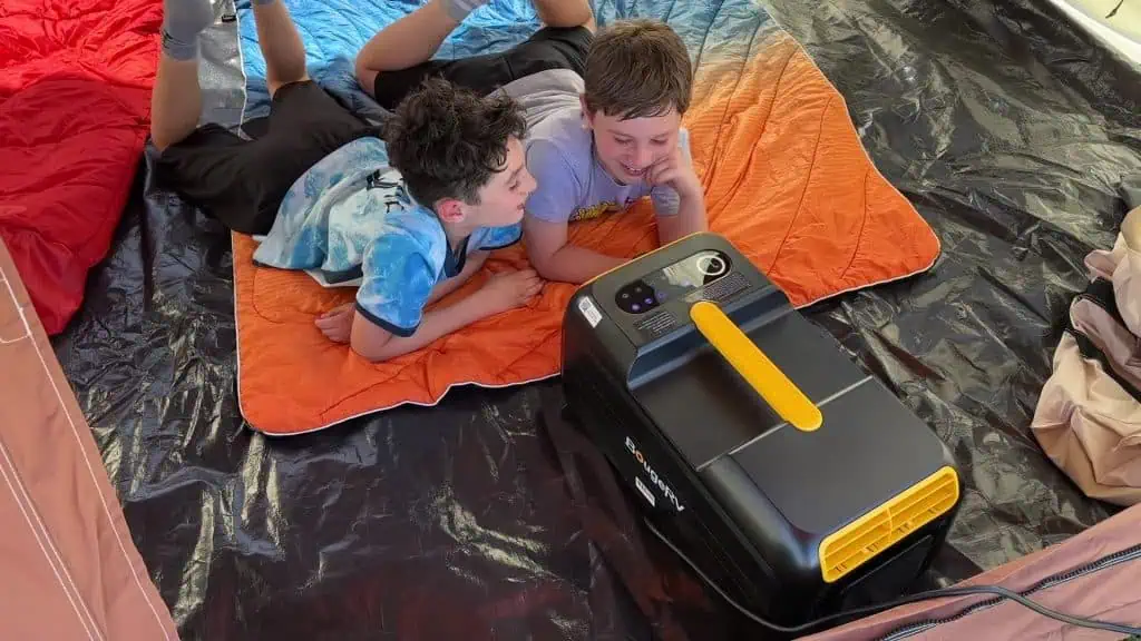Dos campistas en una tienda de campaña junto al aire acondicionado portátil BougeRV 3500BTU durante un viaje de acampada