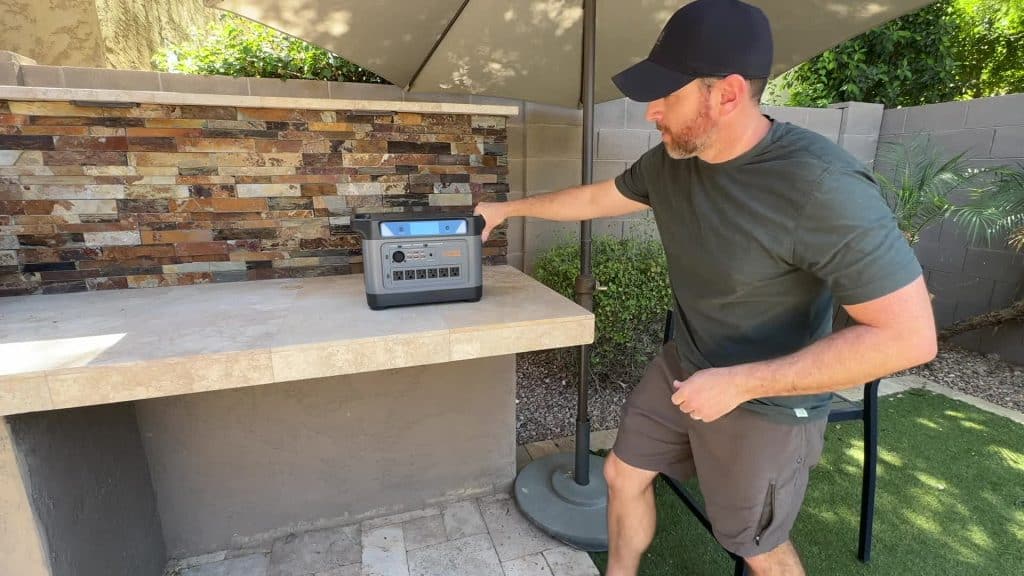 Man using the UDPower S2400 portable power station at an outdoor patio counter for backup power